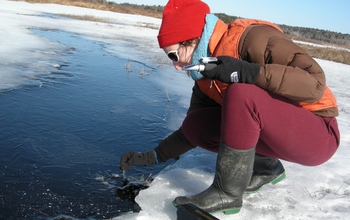 Woman sampling the overlying water of a frozen wetland in Acadia National Park.